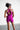Person wearing a bright pink athletic outfit with cut-out design on a plain background