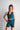 Woman wearing a teal athletic outfit on a plain background