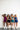 Four women posing together wearing colorful athletic outfits against a white wall.