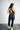 Person wearing a black sports bra and leggings set on a plain background