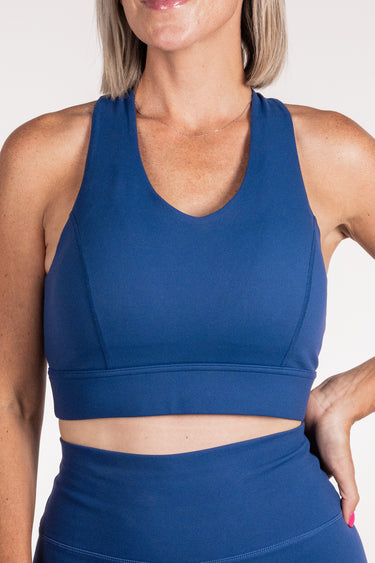 Person wearing a blue sports bra and leggings on a white background