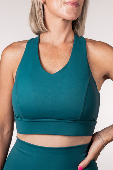 Teal sports bra worn by a person on a plain background
